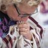 Photo of a woman wearing a tallit and kissing the fringes.