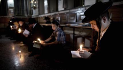 Ultra-Orthodox Jewish men use a candle l