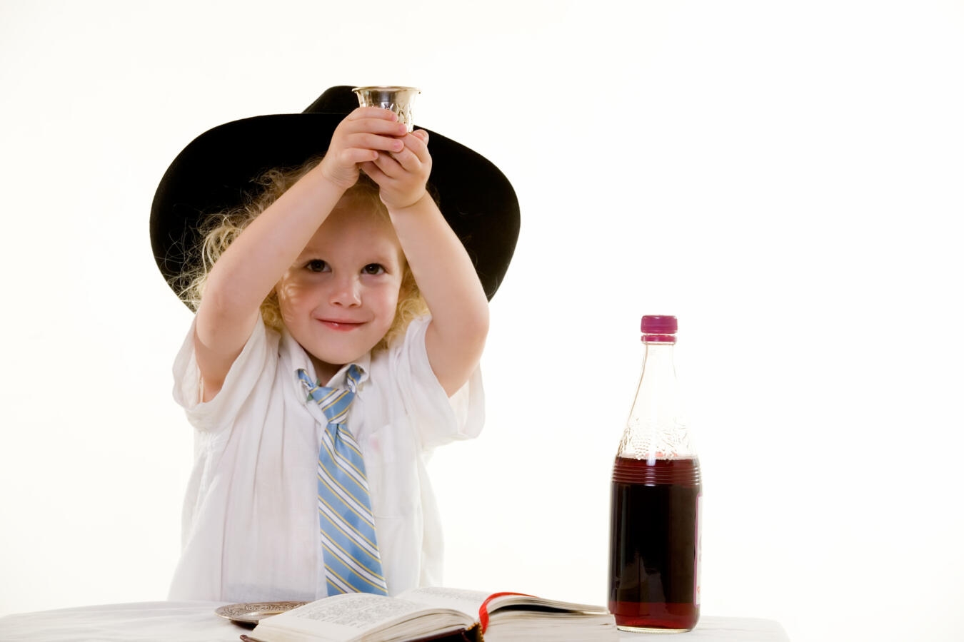 Photo of a young child holding up a kiddush cup.