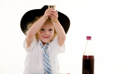 Photo of a young child holding up a kiddush cup.