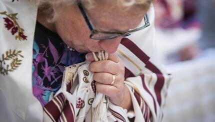 a woman kissing the fringes of a tallit