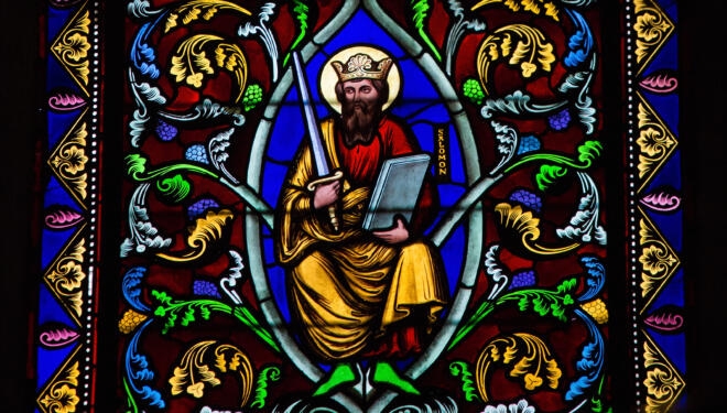 stained glass window depicting a king holding a sword and a book