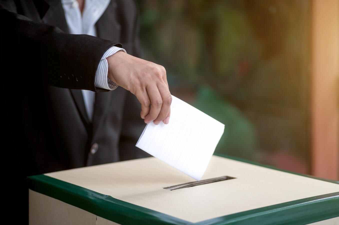 Hand of a person casting a vote into the ballot box during elections