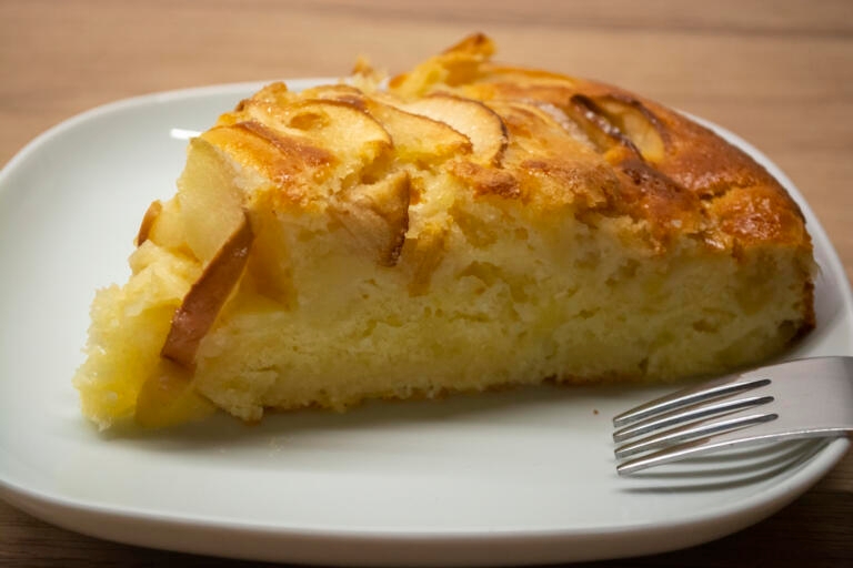 A piece of apple pie on a white plate with a fork. Photo of cake apple kugel recipe easy