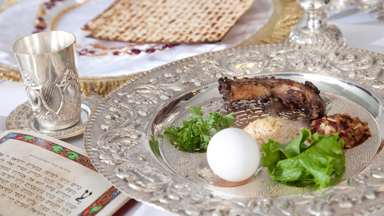 Elements of a traditional Passover seder, including a seder plate, a Kiddush cup for wine, and matzah. The seder plate includes symbolic foods that are related to the Exodus.