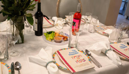 A traditional Passover seder table, featuring a Haggadah, a seder plate, wine and some of the foods enjoyed during the Jewish holiday of Passover