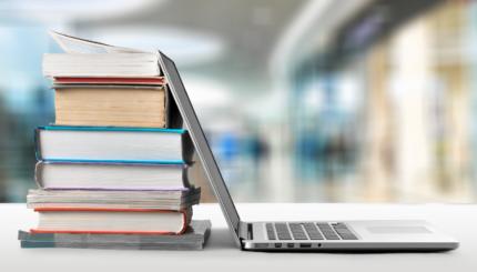 Stack of books with laptop on wooden table