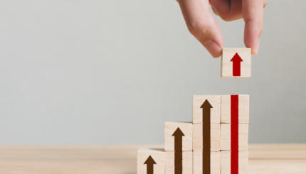 Hand arranging wood block stacking as step stair with arrow up. Ladder career path concept for business growth success process