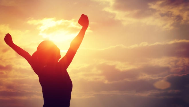 strong confident woman open arms to sunrise at sea