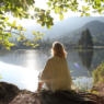 He looks off to distant mountain, forest and lake scene