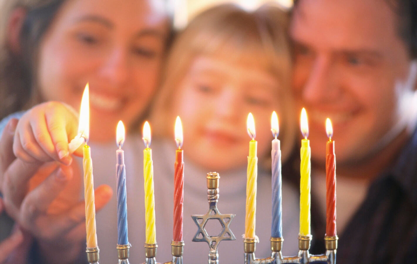 picture of family lighting hanukkah candles