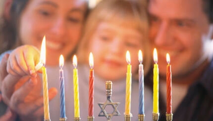 picture of family lighting hanukkah candles