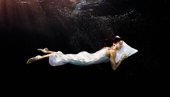 Woman with head on pillow sleeping underwater