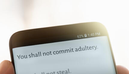 A text message displayed on a mobile phone screen from the Bible's Ten Commandments "You shall not comit adultery"