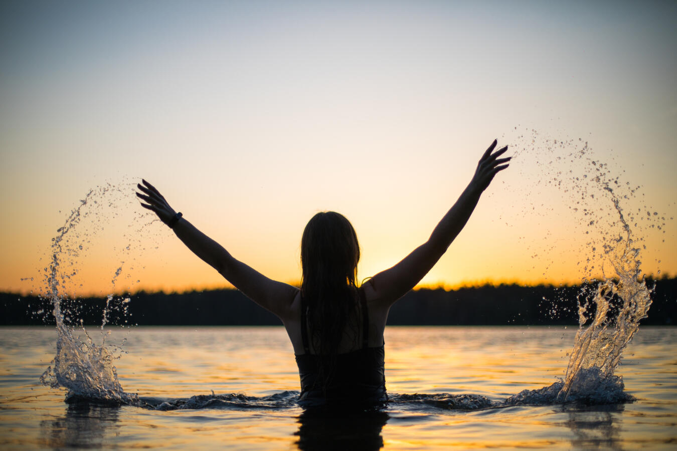 sillhouette of a girl bathing in a river at sunset