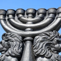 Image of an outdoor, seven-branched menorah flanked by lions.