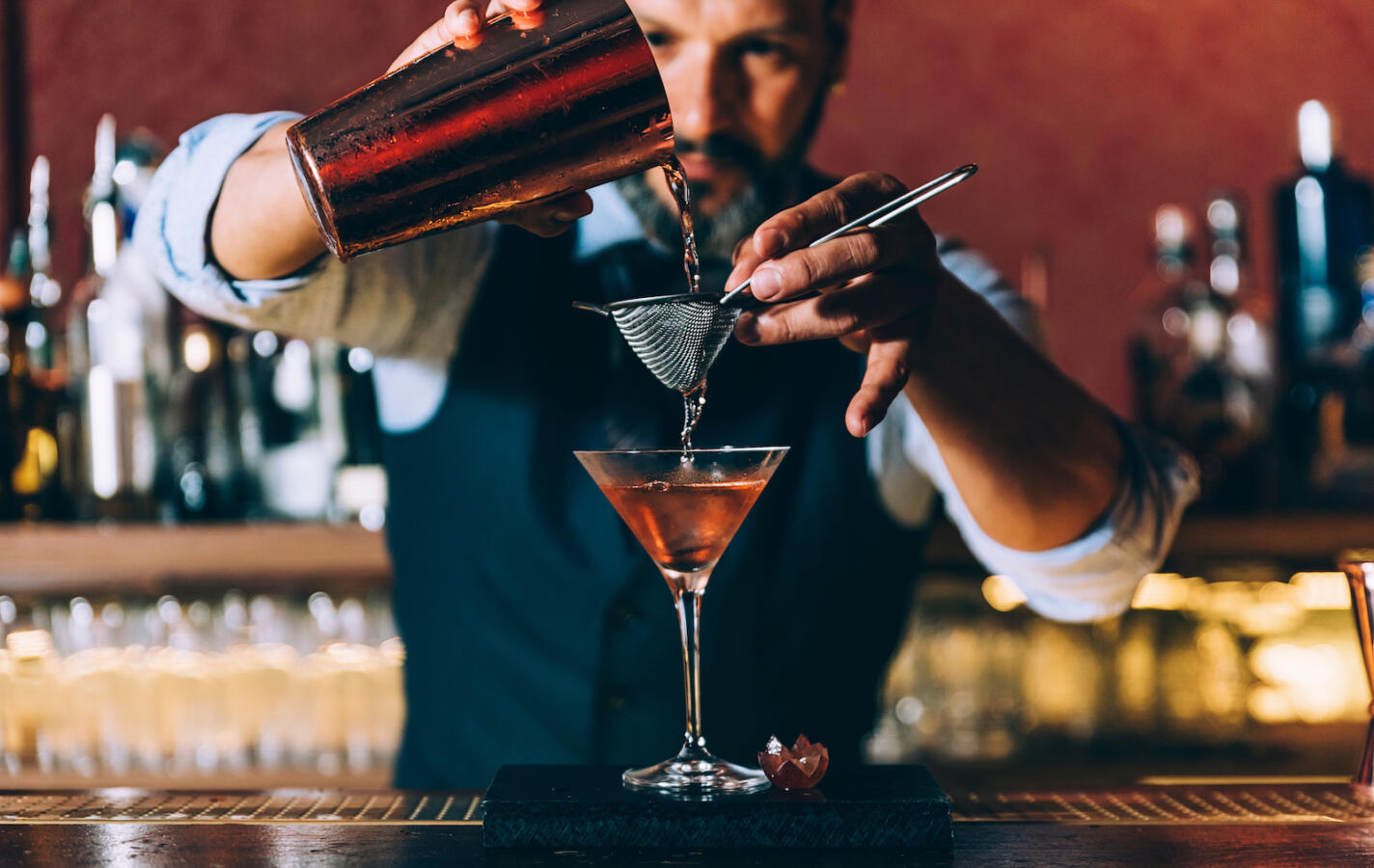 Expert barman is making cocktail at night club.