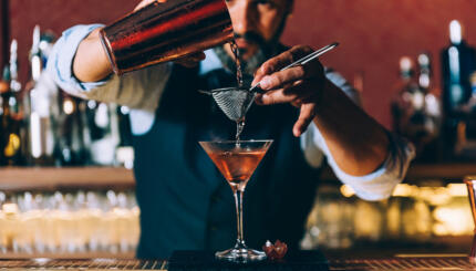 Expert barman is making cocktail at night club.