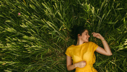 Young girl holding chamomile plant in her hands and enjoying the calm meadow