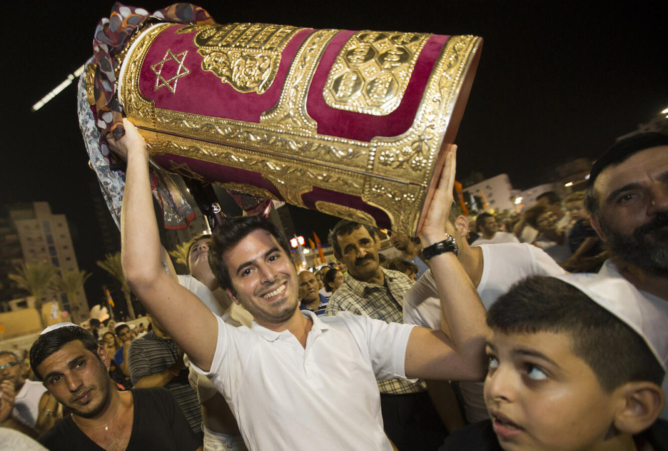 A Jewish man holds a Torah scroll during the Simhat Torah celebration in the Mediterranean coastal city of Netanya, north of Tel Aviv, on September 26, 2013. Simhat Torah is a joyous Jewish celebration that marks the end of the annual cycle of the reading of the entire Torah and the beginning of the new cycle. AFP PHOTO / JACK GUEZ (Photo credit should read JACK GUEZ/AFP via Getty Images)