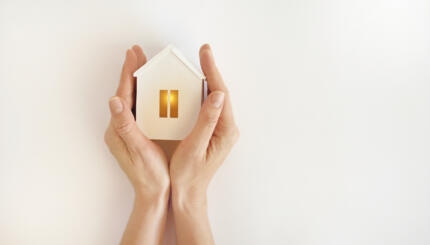 The model of the White House with warm light inside in female hands on a white background