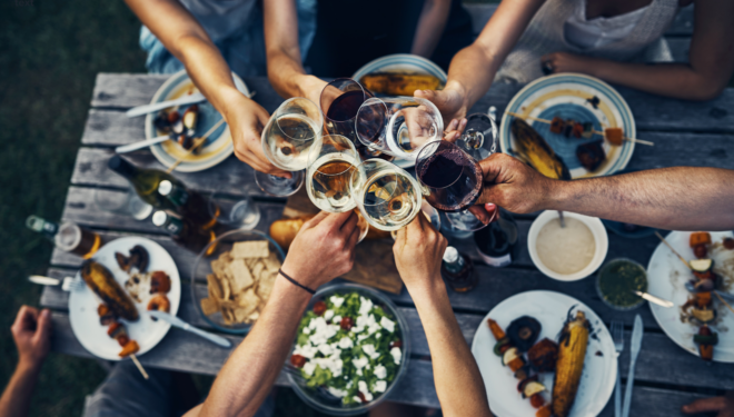 table of food with people holding wine