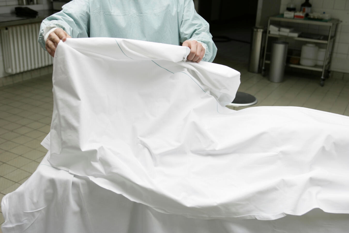 Photo of a doctor removing a sheet from a body